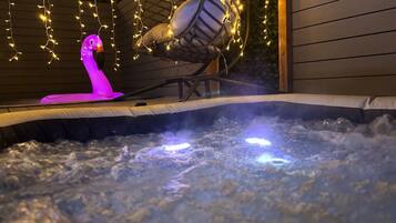 A hot tub with a pink flamingo decoration and a hanging chair with string lights.