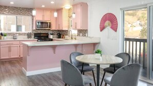 A modern kitchen with pink cabinets, a central island, and a dining area with chairs. - SD Lux Oasis: Theatre, Spa, 14Beds, AC, Sleeps 20+ (Spring Valley)