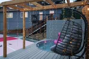 A wooden deck with a hot tub, a pink flamingo chair, and string lights. - SD Lux Oasis: Theatre, Spa, 14Beds, AC, Sleeps 20+ (Spring Valley)
