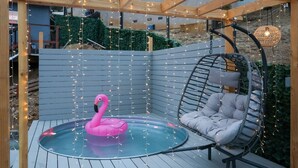 A wooden deck with a hot tub, a pink flamingo float, and a hanging chair. - SD Lux Oasis: Theatre, Spa, 14Beds, AC, Sleeps 20+ (Spring Valley)