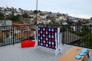 A deck with a bean bag seating area, a bean bag toss game, and a view of a residential area. - SD Lux Oasis: Theatre, Spa, 14Beds, AC, Sleeps 20+ (Spring Valley)