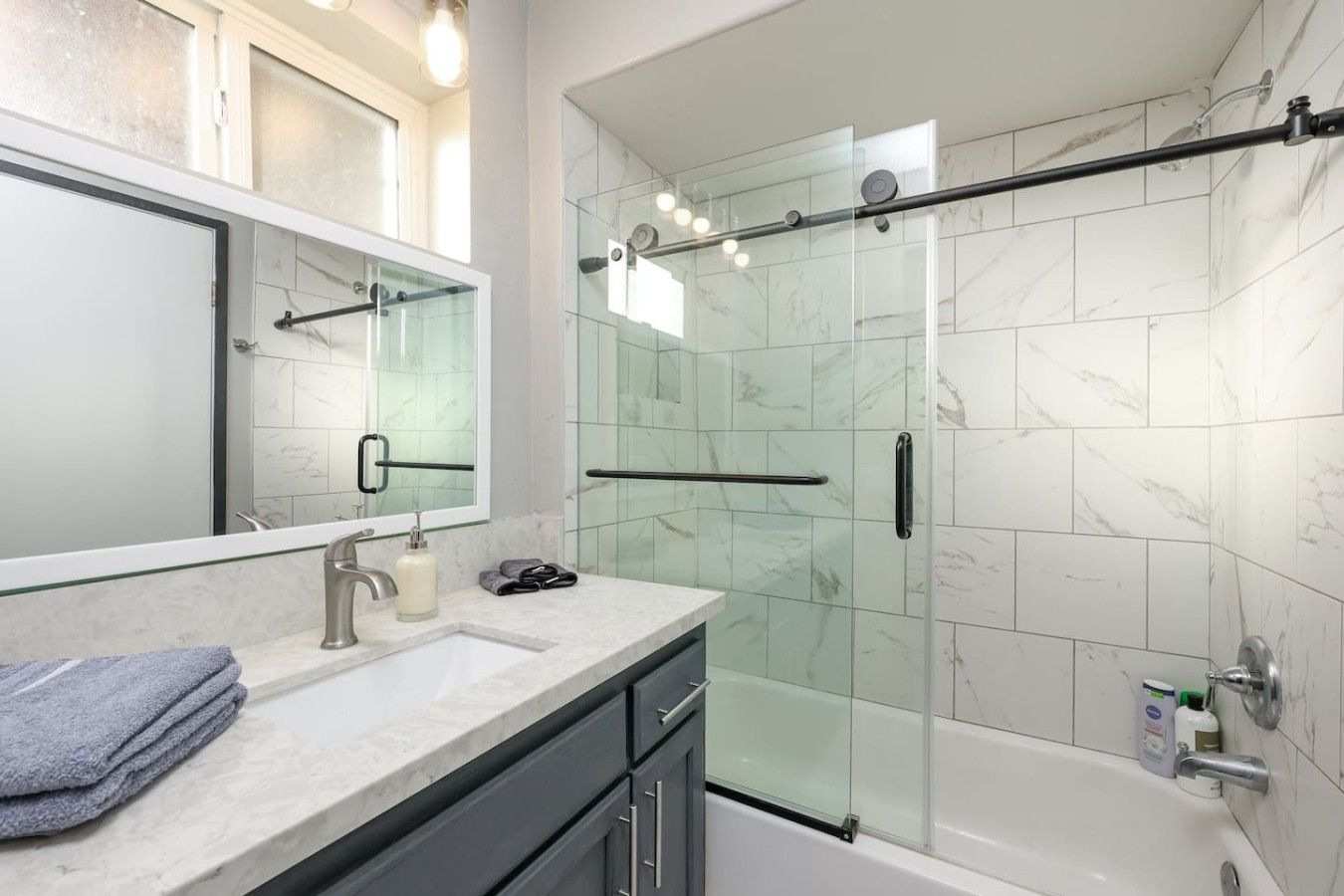 A modern bathroom with a glass shower enclosure, a vanity with a mirror, and a bathtub.