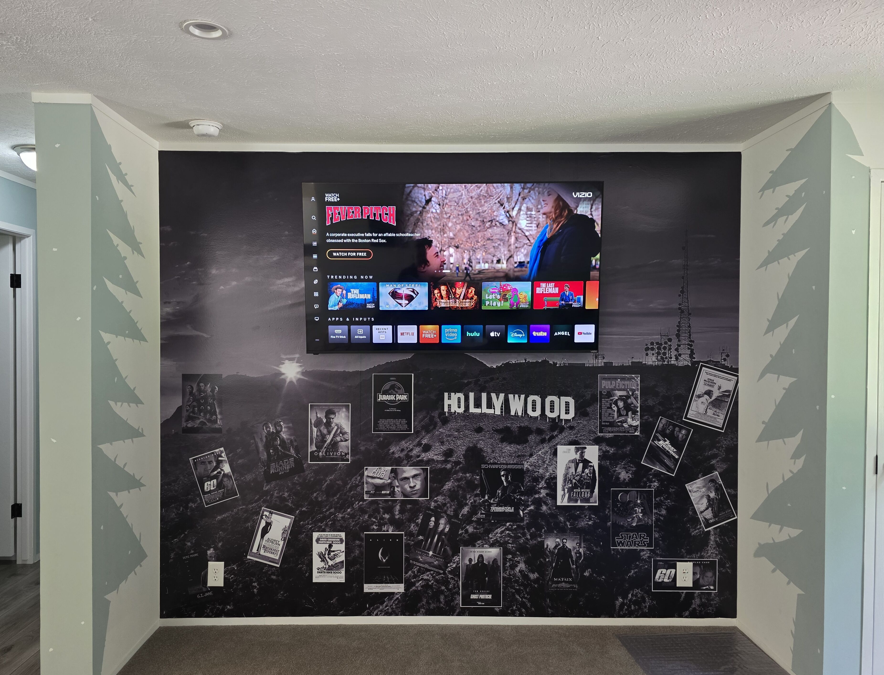 Eine Wand mit einem Flachbildfernseher, der eine Streaming-Dienstanwendung zeigt, umgeben von Filmplakaten.