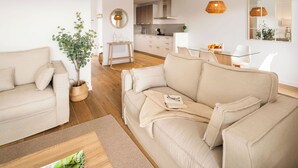 Een moderne woonkamer met een beige bank, een salontafel, en een eetgedeelte met een glazen tafel en stoelen.