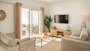 Een moderne woonkamer met een bank, een salontafel, een televisie en een glazen schuifdeur naar een balkon.