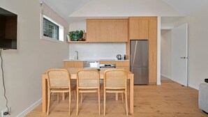 A modern kitchen with wooden cabinets, a stainless steel refrigerator, and a dining table with wicker chairs. - Luxury Stay Next To Iconic Remarkables Mountains (Jacks Point)