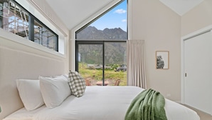 A bedroom with a large bed, a view of mountains, and a window overlooking a garden. - Luxury Stay Next To Iconic Remarkables Mountains (Jacks Point)