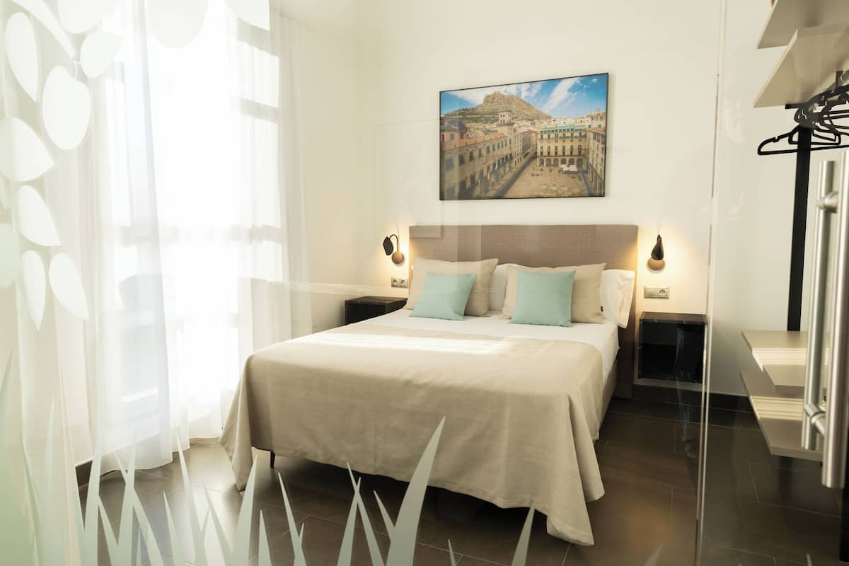 Une chambre à coucher bien rangée, avec un grand lit, deux tables de chevet et un tableau accroché au mur.
