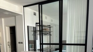 Una sala moderna con un sofá, un separador de vidrio y vista a la cocina.