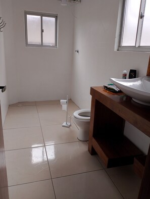 A small, clean bathroom with a toilet, a sink, and a window.