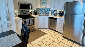 Una cocina moderna con armarios blancos, electrodomésticos de acero inoxidable y salpicadero de azulejos.