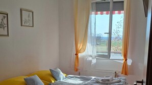 A bedroom with a wooden bed, a window with curtains, and a radiator. - Apartment Golf in  the Spa of Bük, near thermal baths and golf course (Bük)