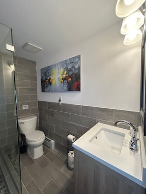 Une salle de bain moderne équipée de toilettes, d’un lavabo et d’une douche.