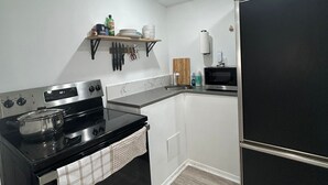 A kitchen with a stove, microwave, and black cabinets.