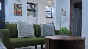 A modern living room with a green sofa, a wooden coffee table, and a painting on the wall.