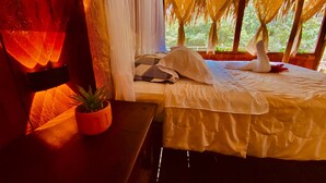 Un lit à baldaquin, une plante en pot et un ordinateur portable posés sur une table en bois.