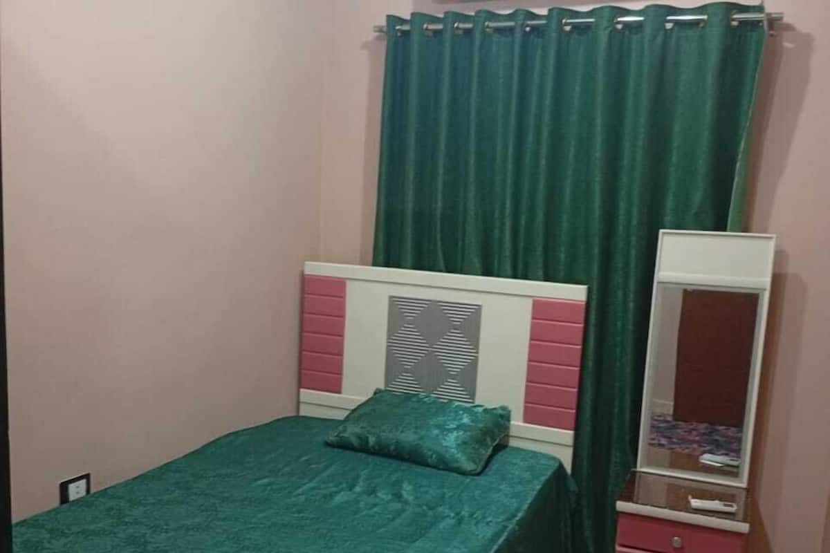 A bedroom with a bed, a dresser, a mirror, and an air conditioner.