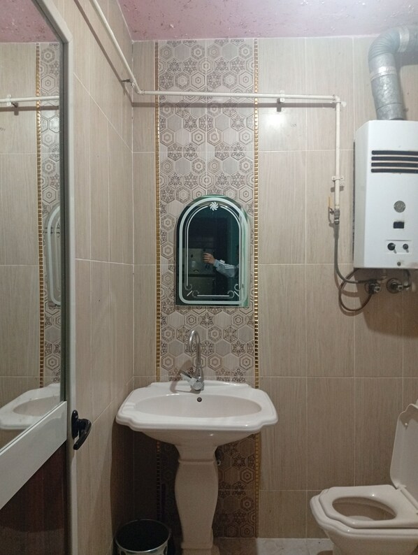 A bathroom with a pedestal sink, a toilet, and a mirror with a decorative frame. - Migo pyramids View (Giza)