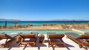 Un espace aménagé au bord de la piscine, avec des chaises longues et une vue sur l’océan.