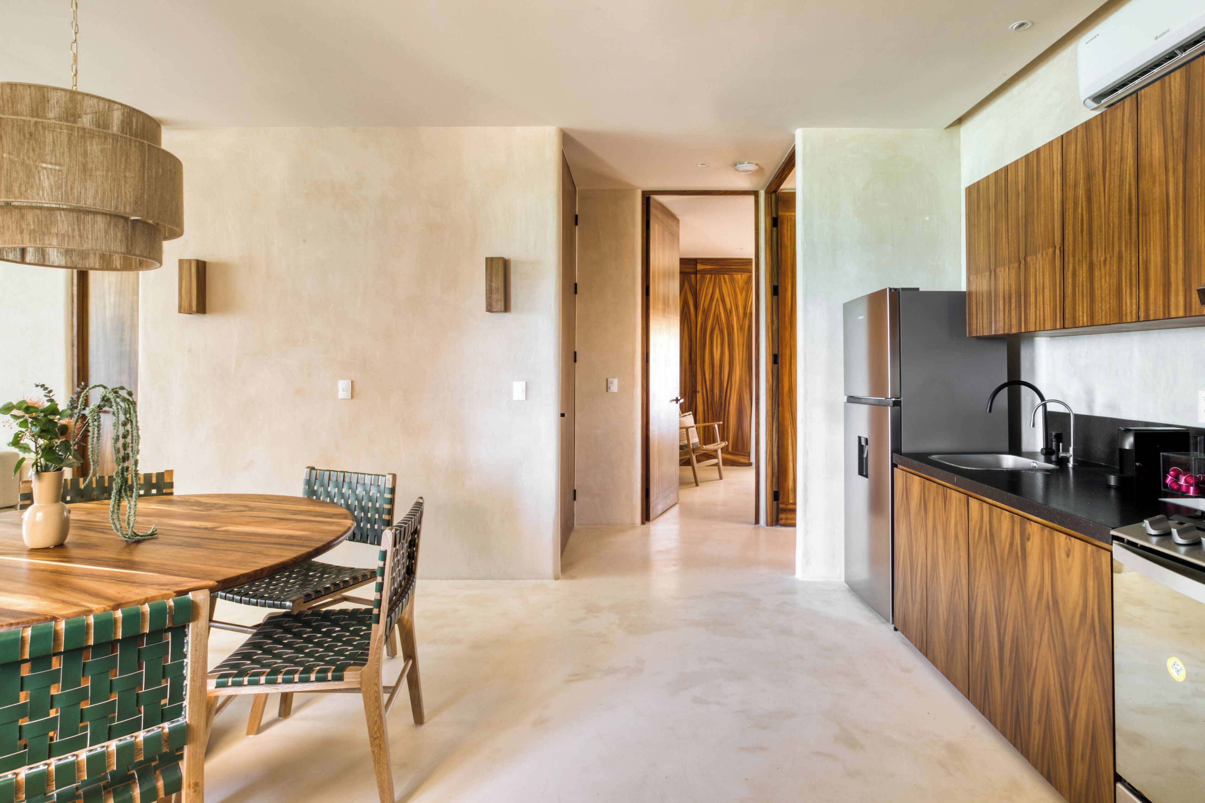 Una cocina moderna con armarios de madera, un refrigerador de acero inoxidable y un comedor con una mesa redonda y sillas.