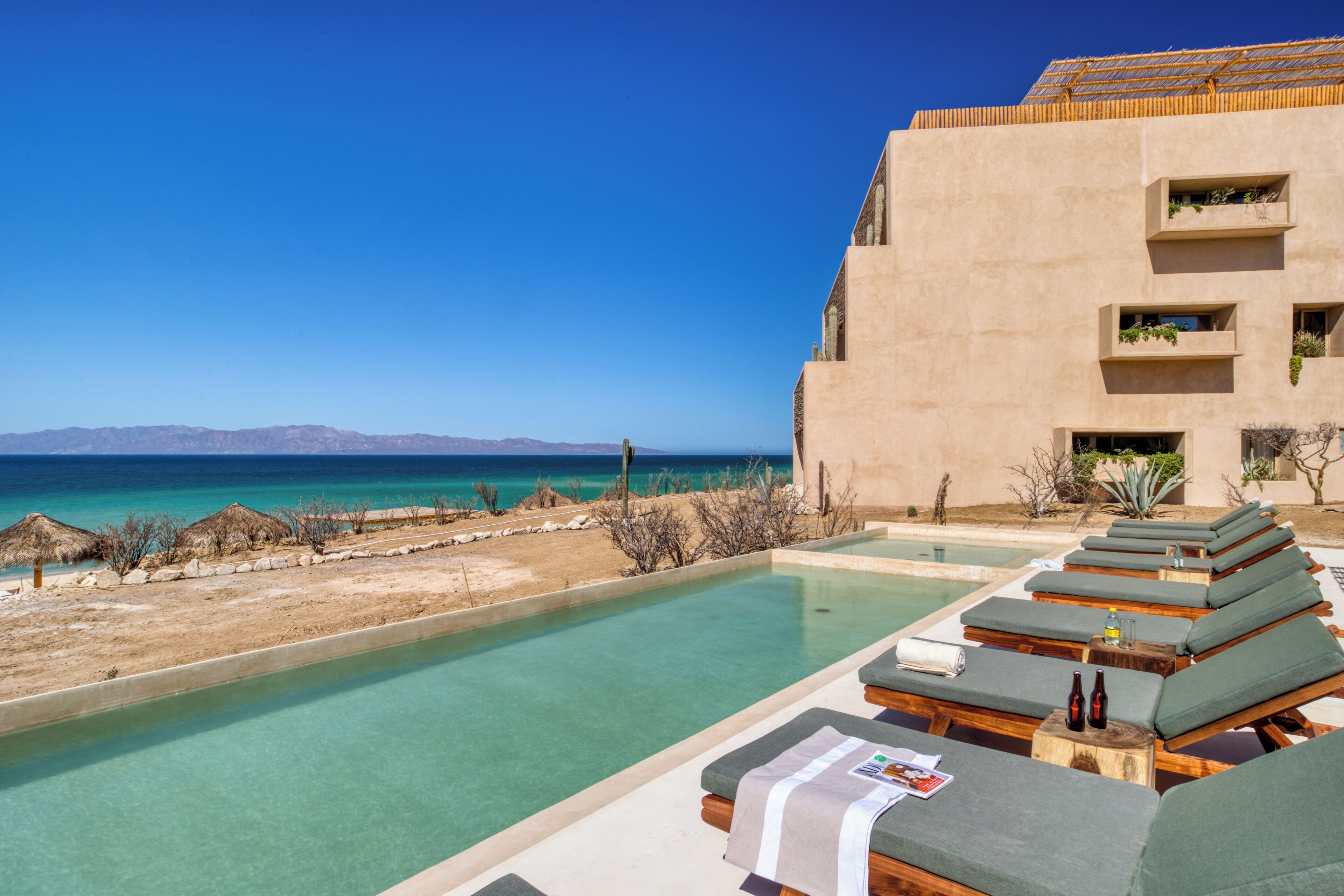 A poolside area with lounge chairs and a view of the sea.