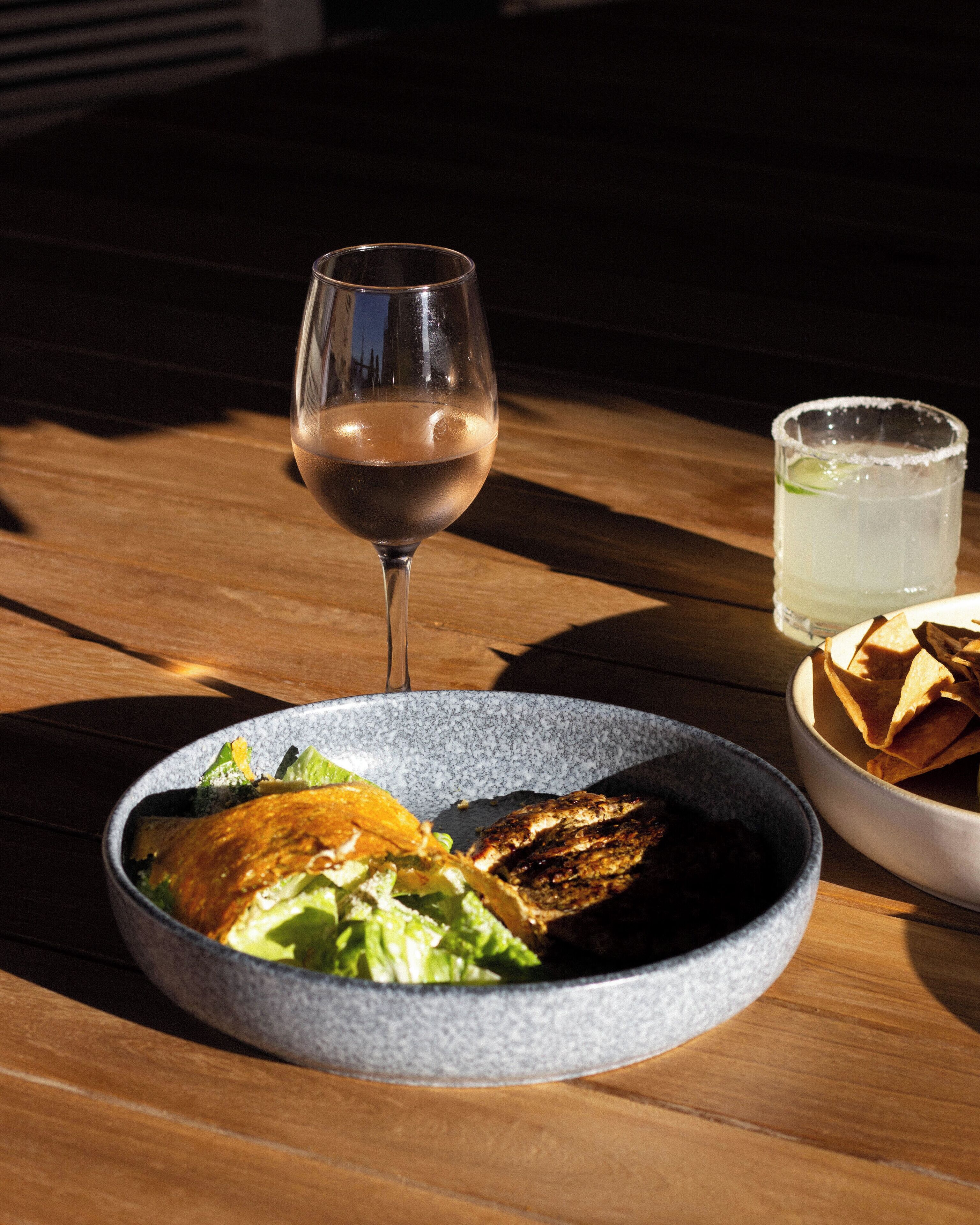 A table with a plate of food, a glass of wine, and a glass of water.