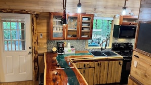 Una cocina rústica con armarios de madera, una isla central, protector de encimera de piedra y vistas al exterior.