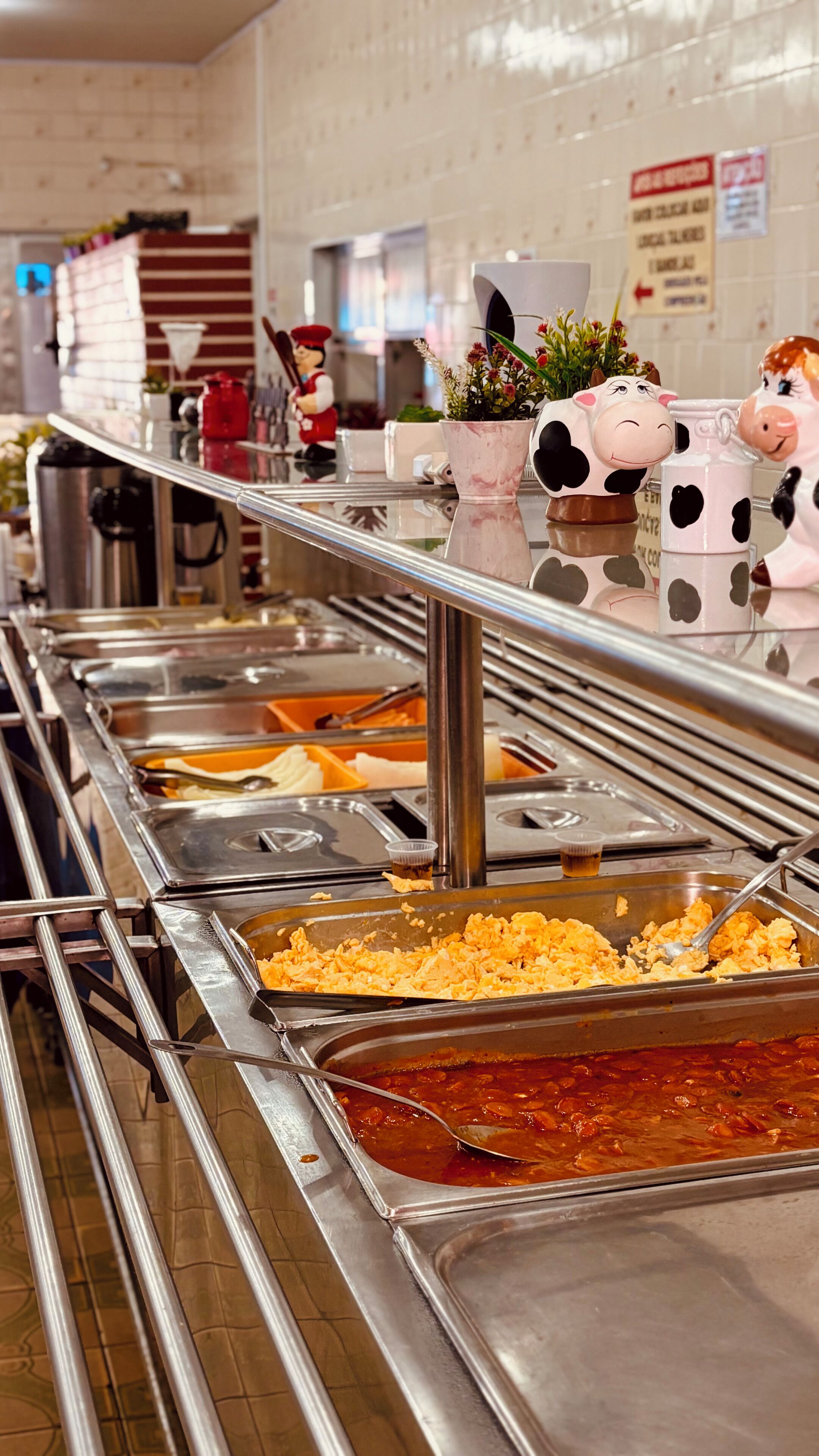 Una barra de buffet con diversas opciones de comida, incluyendo huevos revueltos y chili.