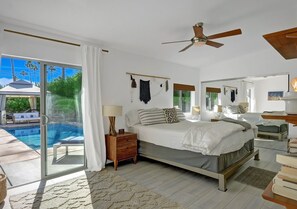 Ein Schlafzimmer mit einem großen Bett, einem Deckenventilator und Blick auf einen Swimmingpool.