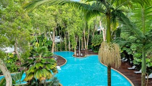 Ein Pool, umgeben von üppiger Vegetation und Bäumen, mit Liegestühlen am Pool.