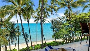 Blick auf einen Strand mit Palmen und einem Stuhl auf einem Balkon.