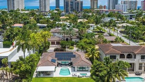 A residential area with a large house featuring a swimming pool, solar panels, and a dock with a boat. - Sunset 4BR Waterfront Villa in Golden Isles w/ Heated Pool & Spa (Hallandale Beach)
