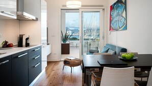 A modern kitchen with a dining area, a view of the marina, and a painting on the wall. - Mobiretreat by Klodge - waterfront design flat (Olbia)