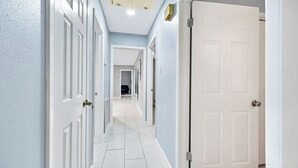 A hallway with white doors, light blue walls, and a tiled floor.