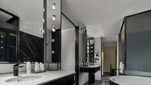 Une salle de bain moderne dotée d’un grand meuble-lavabo, d’un lavabo séparé et d’une baignoire sur pieds.