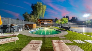 A pool area with lounge chairs, a barbecue setup, and a covered seating area. - Shared fun Pickleball, Theater & Pool | DT Phoenix (Phoenix)