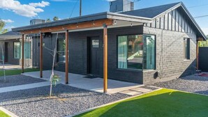 A modern house with a covered porch, large windows, and a well-maintained lawn. - Shared fun Pickleball, Theater & Pool | DT Phoenix (Phoenix)