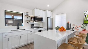 A modern kitchen with white cabinetry, a central island, and a built-in microwave and refrigerator. - Shared fun Pickleball, Theater & Pool | DT Phoenix (Phoenix)