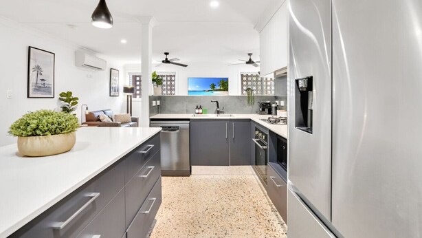 Una cocina moderna con una isla central, electrodomésticos de acero inoxidable y una pantalla de televisión grande.