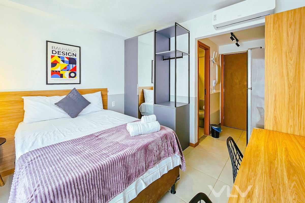 Habitació d'hotel amb llit, mirall, armari i porta al bany.