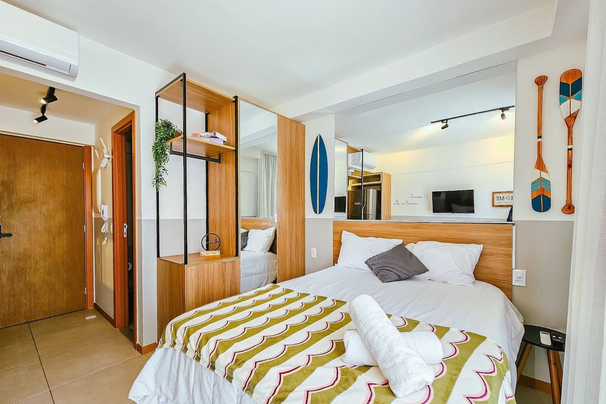 Habitació d'hotel amb un llit, un mirall, un televisor i una porta de fusta.