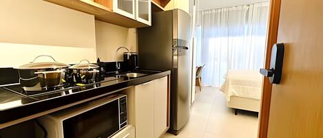 A compact kitchen with a stove, microwave, and refrigerator.
