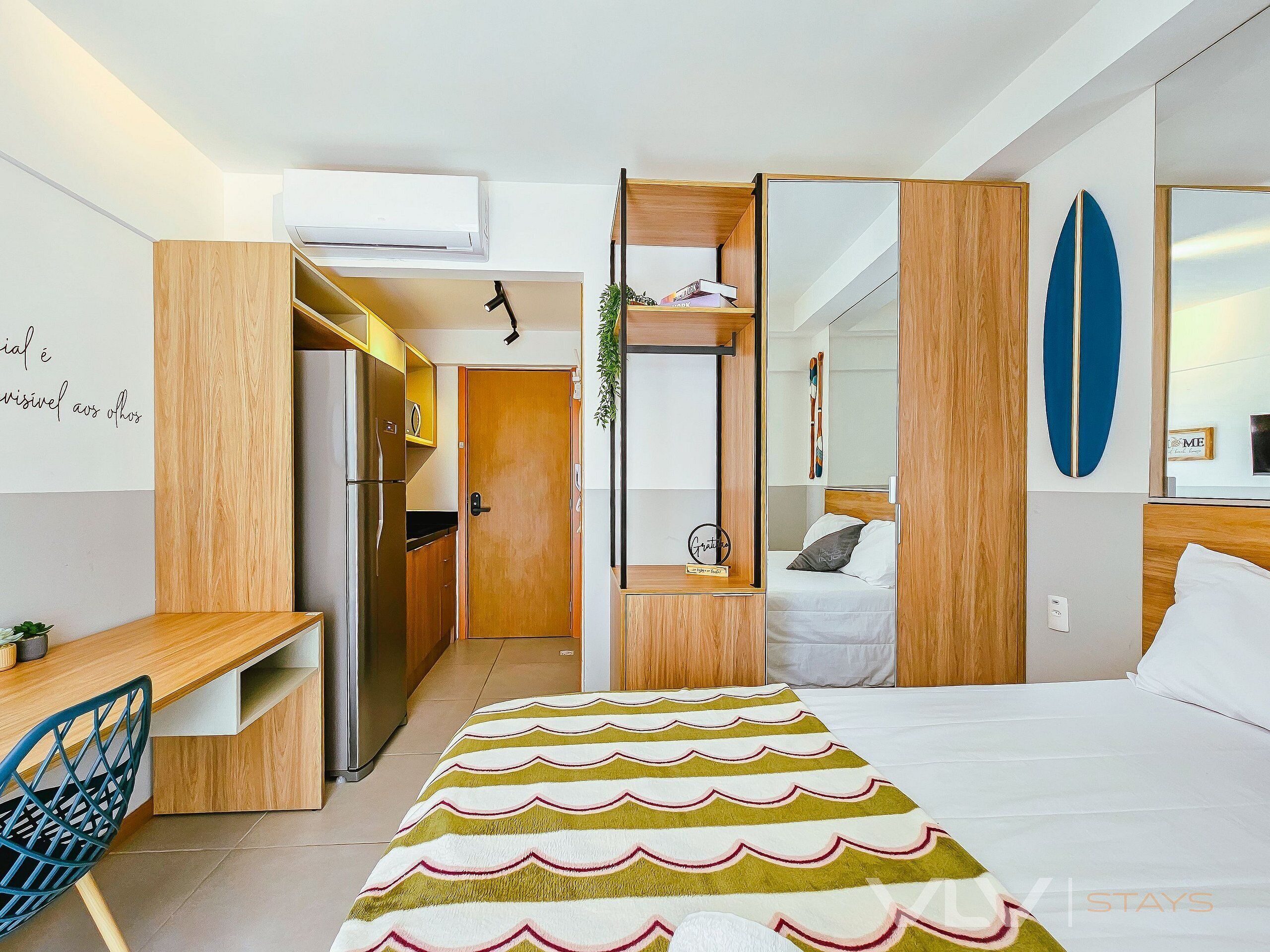 Une chambre d’hôtel moderne équipée d’un lit, d’un bureau, d’une kitchenette et offrant une vue sur l’extérieur.