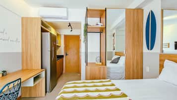 Une chambre d’hôtel moderne équipée d’un lit, d’un bureau, d’une kitchenette et offrant une vue sur l’extérieur.