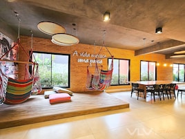 A modern interior with a brick wall, large windows, a hammock chair, and a wooden table.