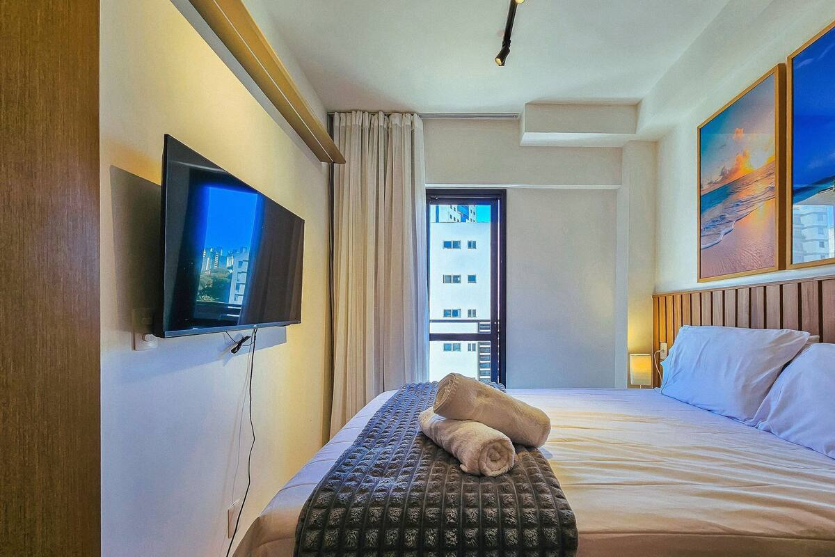 Habitació d'hotel amb un llit, una televisió, una finestra amb cortines i un quadre a la paret.
