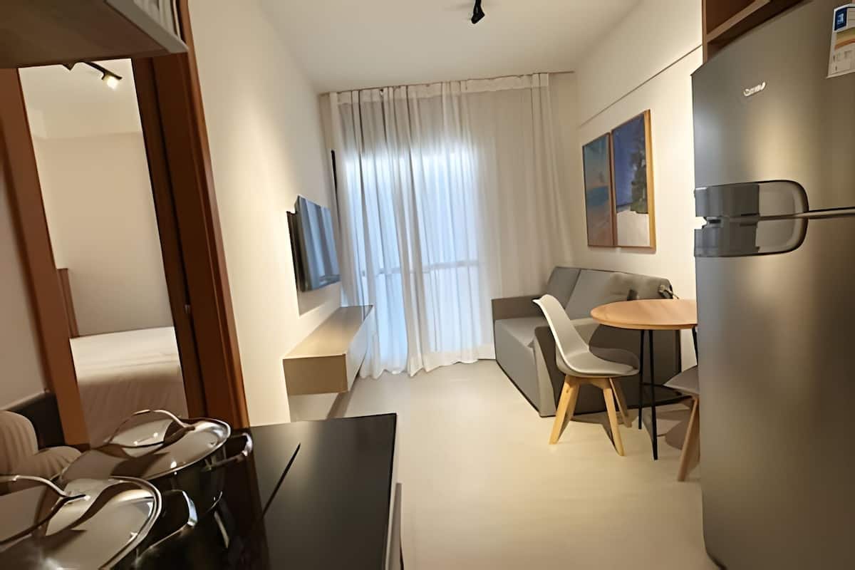 Habitació d'hotel amb llit, televisió, sofà, taula de dinar amb cadires i nevera.