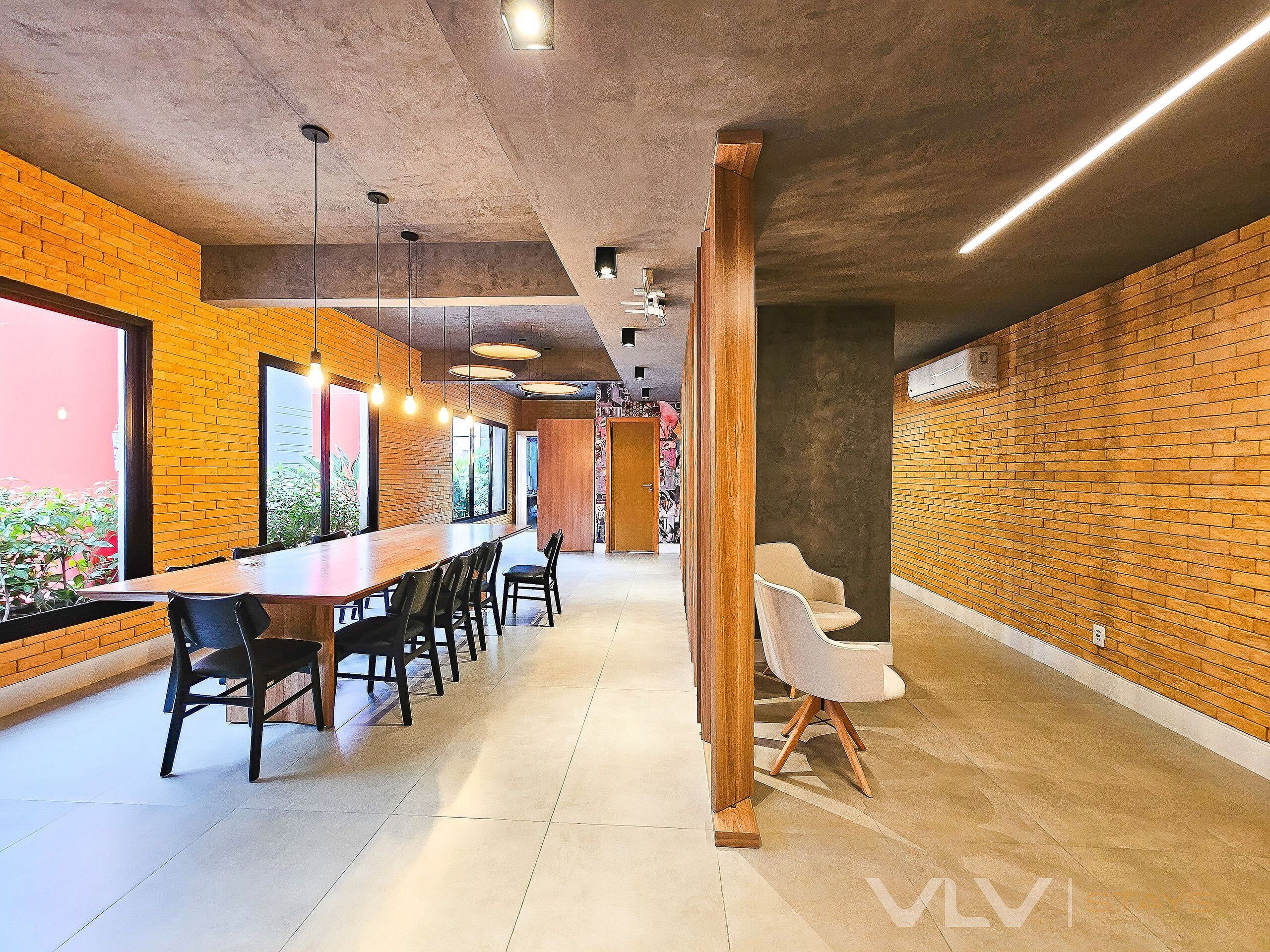 A modern interior with a long wooden table, black chairs, and a brick wall.