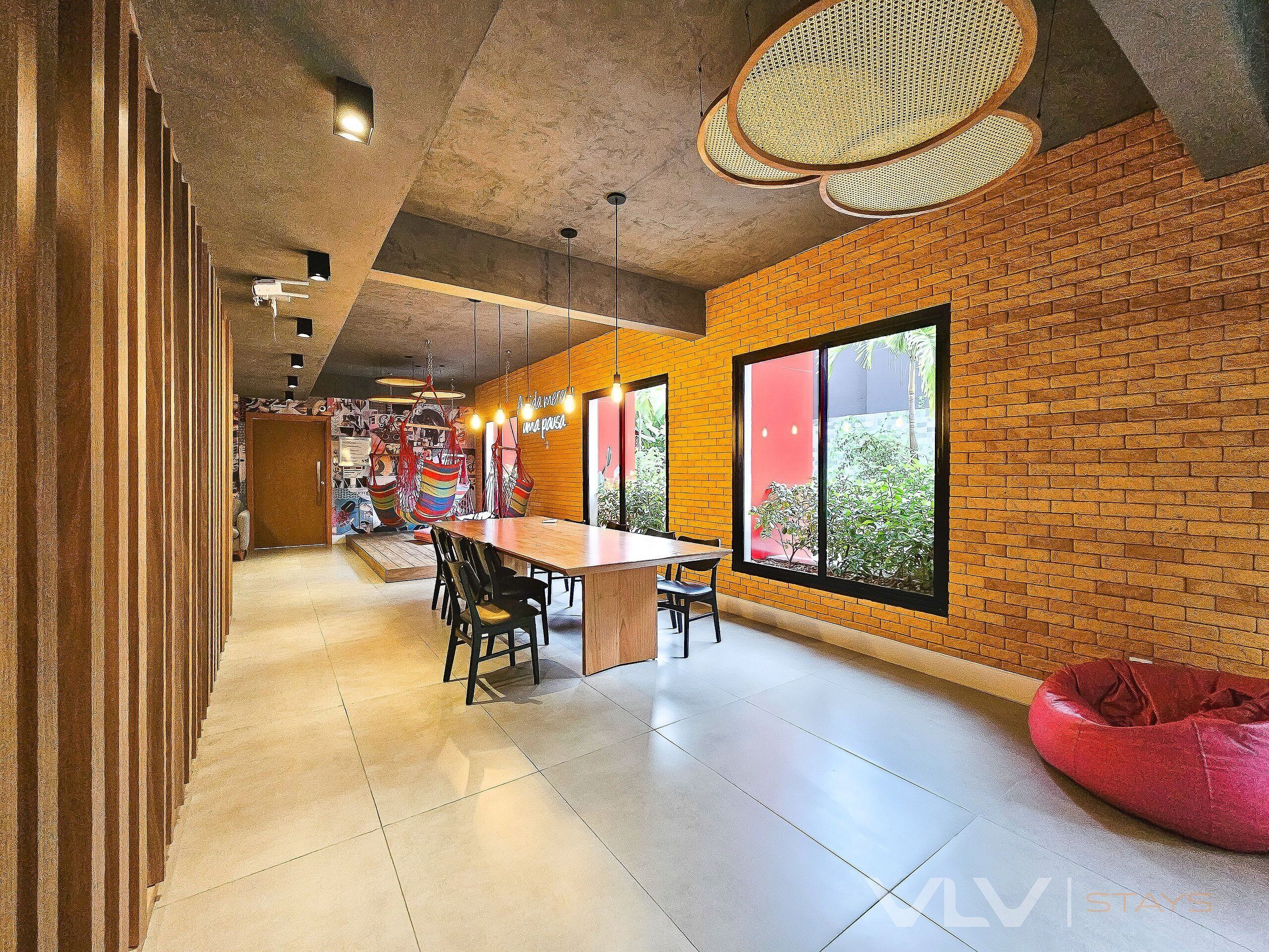 Un interior moderno con una larga mesa de comedor, sillas colgantes y un sillón de cuero rojo.