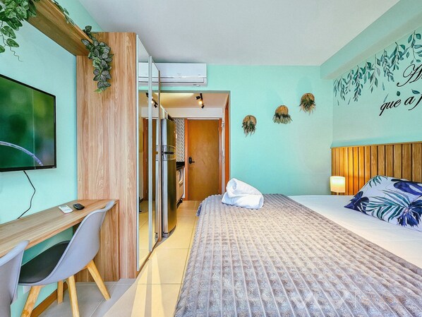 A hotel room with a bed, a desk, a TV, and a door leading to a bathroom. - Porto Privilege by VLV Stays (Salvador)